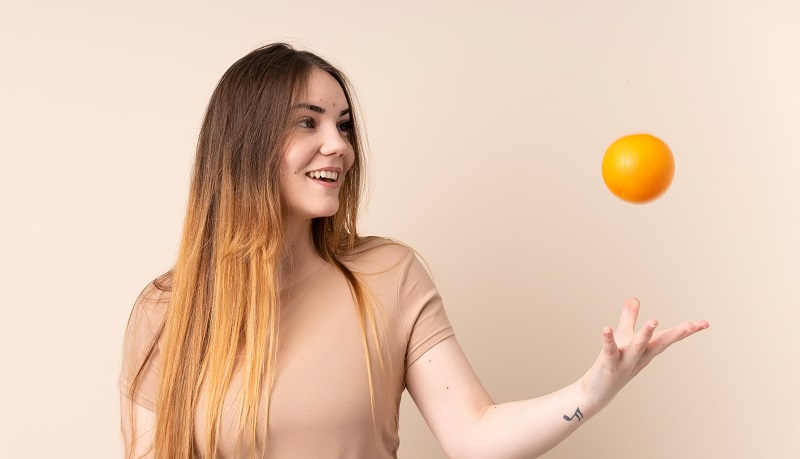 mujer jugando con naranja
